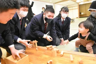 雨竜高等養護学校木工科の生徒と一緒に、手作りの積み木で遊ぶ惟暉ちゃん（右手前）