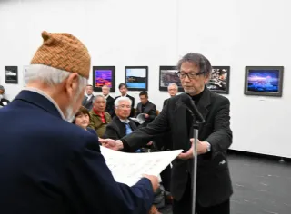 写真道展で大賞に選ばれ、賞状を受け取る鈴木佳夫さん（右）＝26日、札幌市中央区