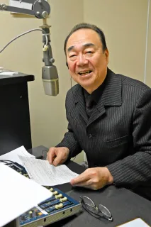 ラジオブースに座る久保村さん。25年間、音楽の魅力を発信し続けてきた