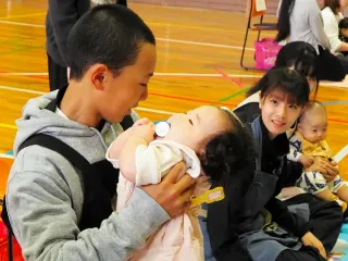 赤ちゃんと楽しそうに触れ合う生徒たち